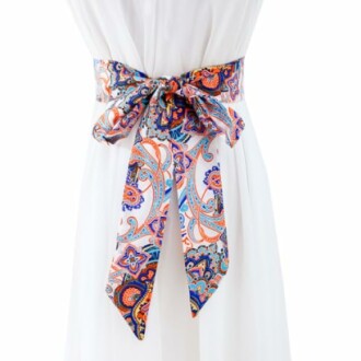 Colorful paisley sash belt tied around a white dress