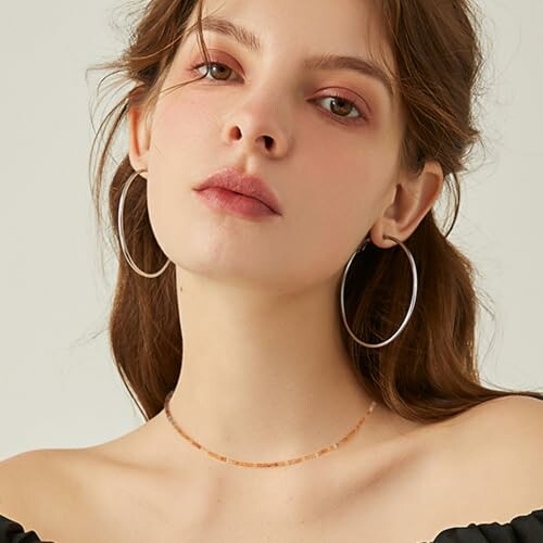 Woman wearing hoop earrings and black top.