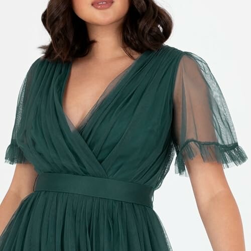 Woman wearing a green dress with tulle sleeves.