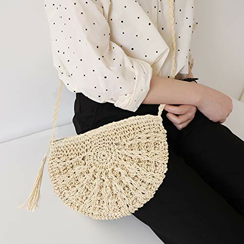 Person holding a handmade straw handbag with a half-moon shape.