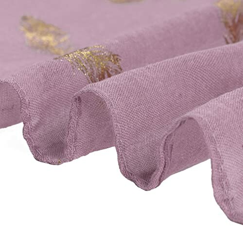 Close-up of purple fabric with gold leaf pattern.