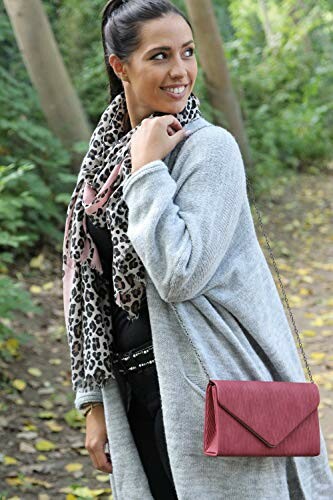 Woman in gray coat with a leopard print scarf and red purse in a forest setting.