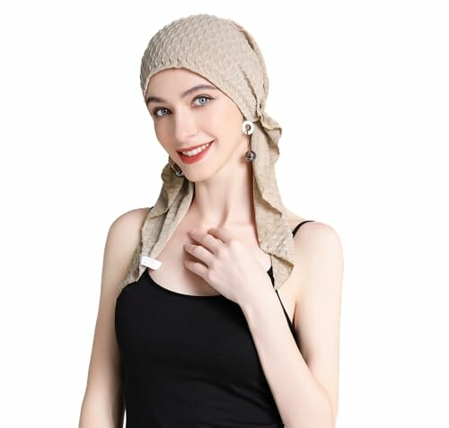 Woman in beige headscarf and black top smiling