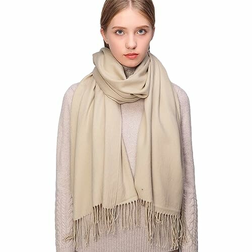 Woman wearing a large beige scarf over a sweater.