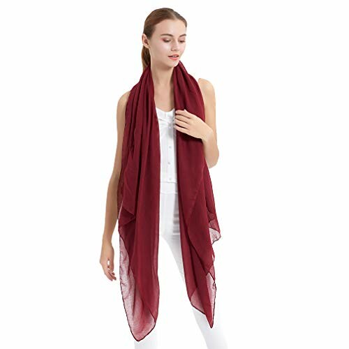 Woman wearing a long burgundy scarf over a white outfit.