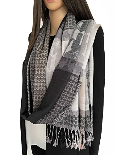 Woman wearing a black and gray patterned scarf with fringe.