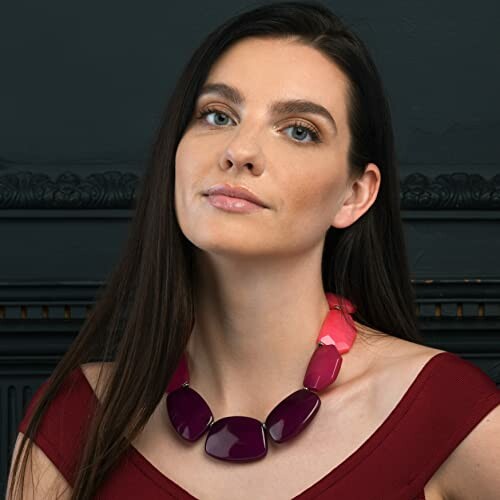 Woman wearing a bold statement necklace with large purple stones.