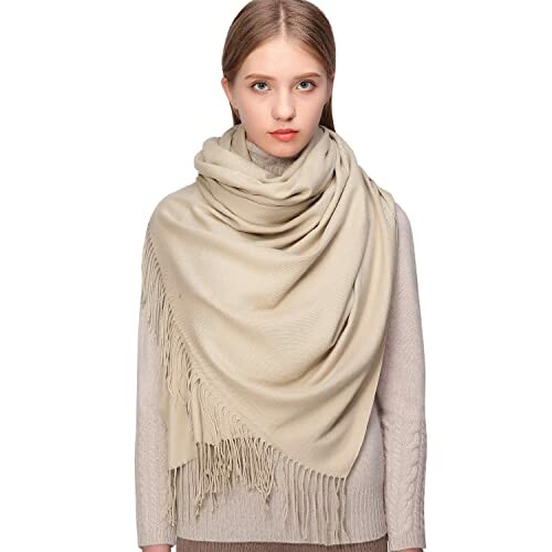 Woman wearing a beige scarf with fringe.