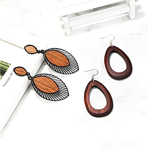 Two pairs of wooden drop earrings on a white surface.